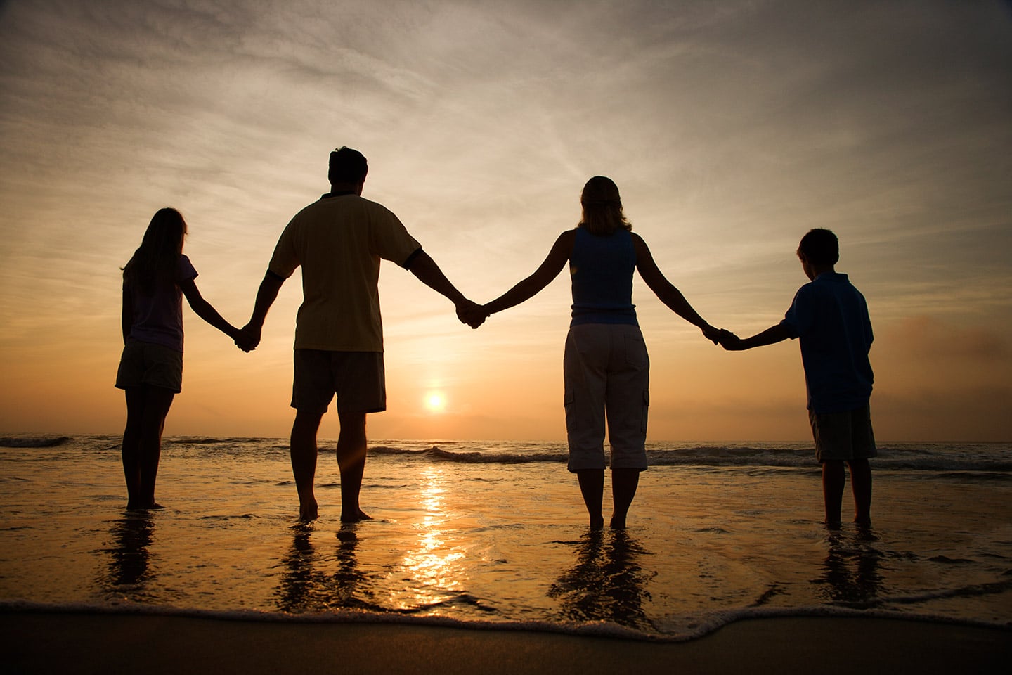 Family holding hands with a Sunset in the background